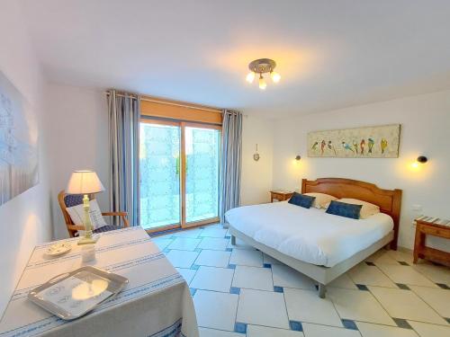 a bedroom with a bed and a table and a window at Gite de Kerantum in Mahalon