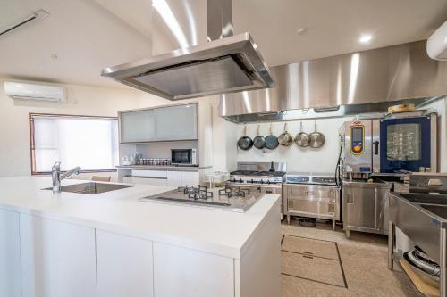 a large kitchen with white counters and stainless steel appliances at Grand Maison W 館山美食倶楽部 in Tateyama
