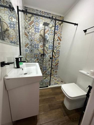 a bathroom with a sink and a shower with a toilet at Flora Racha - Lovely Cottages in Ambrolauri