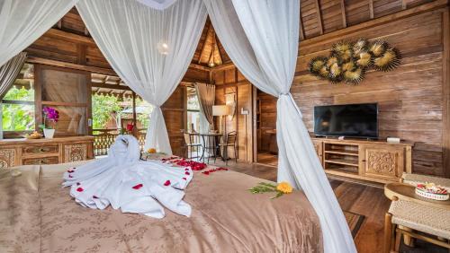 a bedroom with a bed with a white canopy at Kirani Joglo Villa Bali by Mahaputra in Sukawati