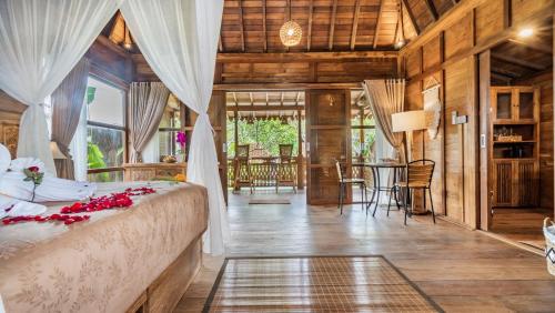 a bedroom with a bed and a dining room at Kirani Joglo Villa Bali by Mahaputra in Sukawati