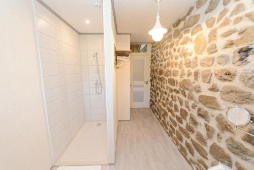 a bathroom with a stone wall and a walk in shower at Nuits D'y Cîmes : Nuit Insolite Bulle, SPA in Jaunac