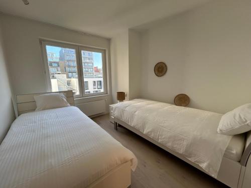 twee bedden in een kamer met een raam bij ASTRID 0301 - App voor 6 personen in De Panne