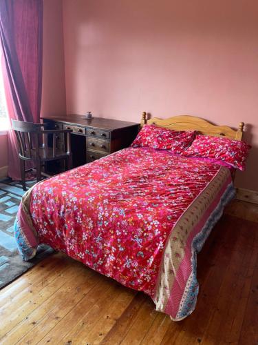 a bedroom with a bed with a red comforter and a desk at Lovely double room in very good area in Edinburgh