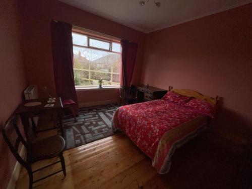 a bedroom with a bed with a red comforter and a window at Lovely double room in very good area in Edinburgh