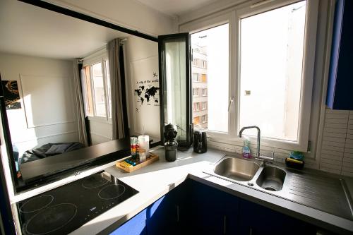 une cuisine avec un évier et deux fenêtres dans l'établissement Luxury Appartement Batignole, à Paris