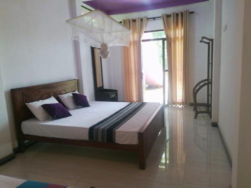 a bedroom with a bed with purple pillows at Tezara Home Stay in Sigiriya