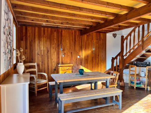 d'une salle à manger avec une table, des chaises et des murs en bois. dans l'établissement Au Petit Bonheur, à Camprieu