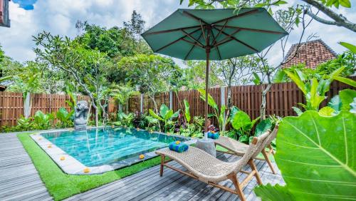 a pool with two chairs and an umbrella at Kirani Joglo Villa Bali by Mahaputra in Sukawati