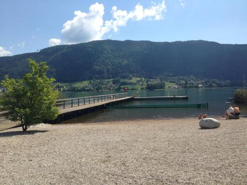 a bridge over a lake with people sitting on the beach at Familienurlaub am See in Bodensdorf