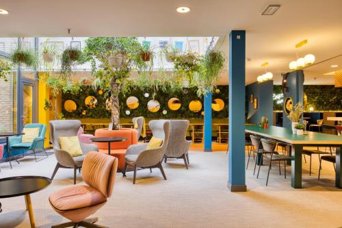 una sala de espera con sillas, mesas y plantas en B&B HOTEL Brussels Centre Louise en Bruselas