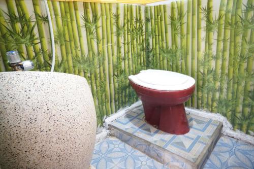 baño con aseo rojo en una pared de bambú en Collection O 93000 Karona Berg Homestay & Cafe, en Banyuwangi