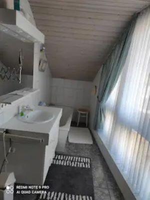 a white bathroom with a sink and a window at Ferienhaus Kirschblüte in Wolfshagen im Harz in Wolfshagen
