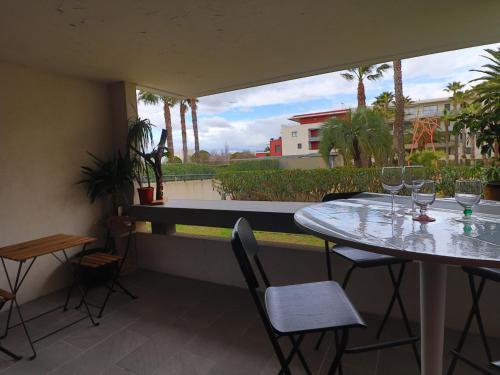 d'une table et de chaises avec des verres à vin sur le balcon. dans l'établissement Charmant 2 pièces avec piscine à Sète, proche plage et commerces - FR-1-472-192, à Sète