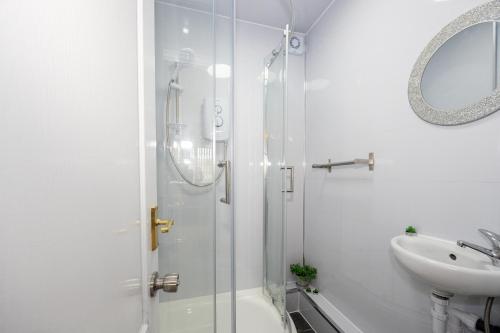 a white bathroom with a shower and a sink at Airstays Apartment in Wythenshawe