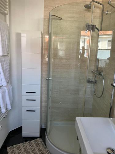 La salle de bains est pourvue d'une douche et d'un lavabo blanc. dans l'établissement Jenszu Ferienwohnung, à Balingen
