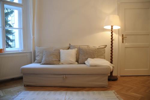 um sofá com almofadas e um candeeiro num quarto em Lovely Renovated Apartment Top 11 - Easy Self Check in em Viena