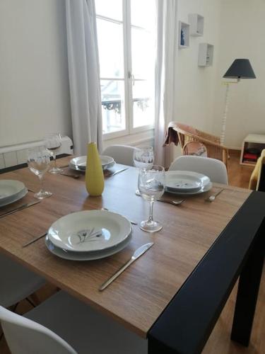 une table en bois avec des assiettes et des verres à vin dessus dans l'établissement Au coeur de Dieppe, au puits salé, à Dieppe