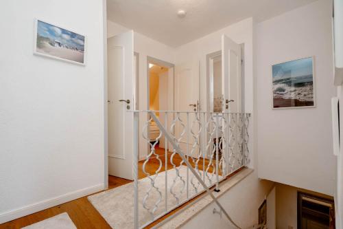 a hallway with white walls and a staircase with a glass door at Ferienhaus Sprotte in Tinnum