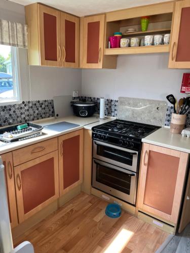 a kitchen with a stove and wooden cabinets at Caravan in Mablethorpe