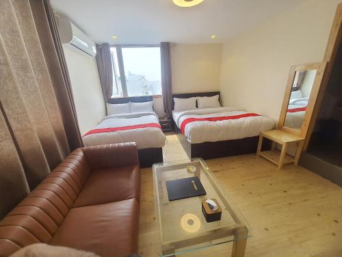 a room with two beds and a couch and a table at Hotel Odaan in Kathmandu