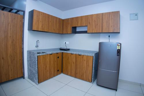 cocina con nevera y armarios de madera en 24 CARAT STUDIO APARTMENTS en Porbandar