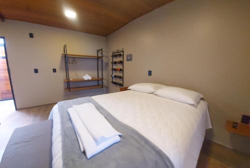 a bedroom with a large white bed with two towels on it at Pousada Bégamo - Vale dos vinhedos in Bento Gonçalves
