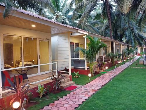 a house with a green lawn and a house with palm trees at The Sunbliss Cottages in Morjim