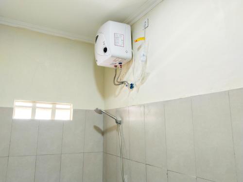 La salle de bains est pourvue d'une douche blanche et d'une caméra murale. dans l'établissement Yayah Guest House Syariah by Cocotel, à Bubulak 3