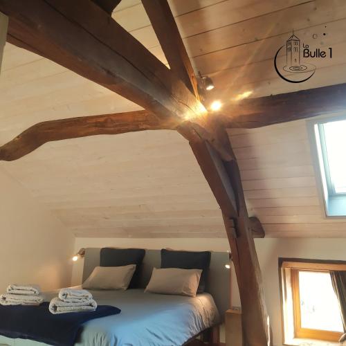 un lit dans une chambre avec un plafond en bois dans l'établissement la bulle de Chapaize, à Chapaize