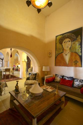 een woonkamer met een bank en een schilderij van een vrouw bij Riad Le Palais du Caid. SIecle XVIII in Tozeur