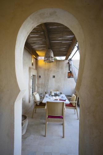 een tafel en stoelen in een kamer met een boog bij Riad Le Palais du Caid. SIecle XVIII in Tozeur