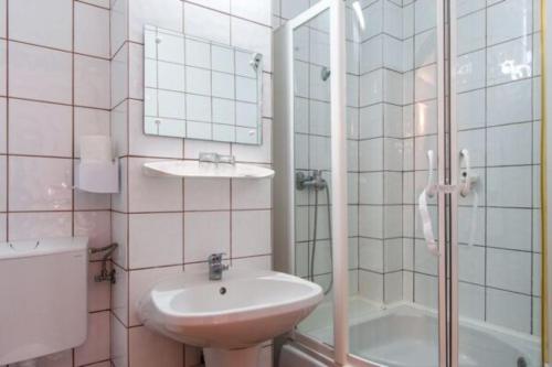 uma casa de banho com um lavatório, um chuveiro e um WC. em Hotel Alice em Băile Olăneşti