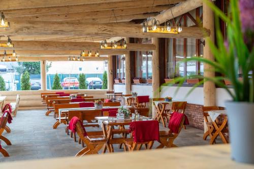 un restaurante con mesas de madera y sillas con servilletas rojas en Pensiunea Koronka, en Corunca