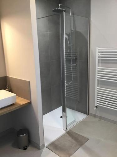une douche avec une porte vitrée dans une salle de bain dans l'établissement Au coeur d'Omaha Beach- Colleville-sur-Mer- Gîte 2, à Colleville-sur-Mer