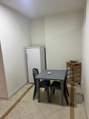 a table and two chairs in a room with a refrigerator at ستوديو فينيسيا in Sfax