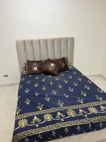 a bed with a blue blanket and pillows on it at ستوديو فينيسيا in Sfax