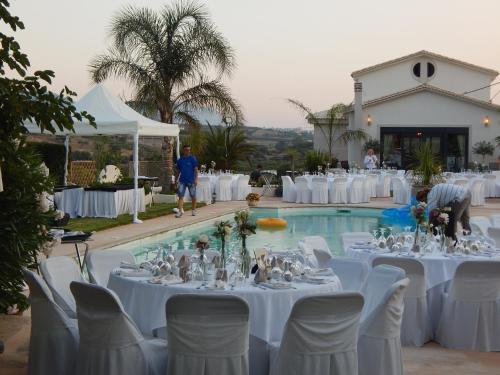 a group of tables and chairs in front of a pool at Villa Vravrona Tower & Suites in Markopoulo