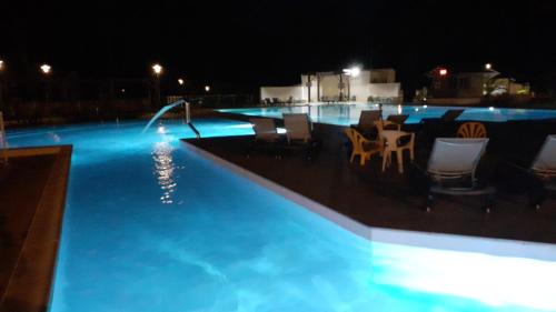 uma piscina à noite com cadeiras e uma fonte em CHALET B NATURISTE NAEVA em Le Porge