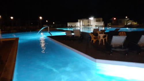 a swimming pool at night with chairs and a fountain at CHALET B NATURISTe MAEVA in Le Porge