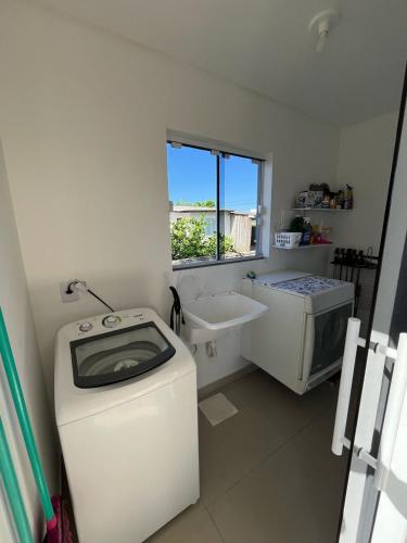 y baño con lavadora y lavamanos. en Casa com piscina en Capão da Canoa