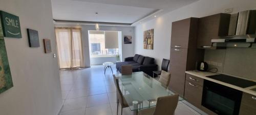 a kitchen and a living room with a glass table at VBH APARTMENT PACEVILLE ST. JULIAN'S in Paceville