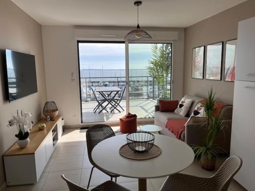 a living room with a couch and a table and chairs at Appartement standing vue étang de Thau in Marseillan