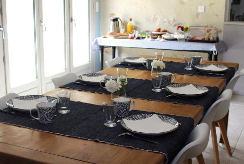 a dining room table with black and white plates and napkins at Au bois Noël - Le Cerisier in Lescherolles