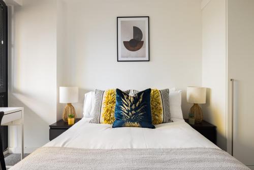 um quarto com uma cama branca e 2 candeeiros em The Sloane Apartment em Londres