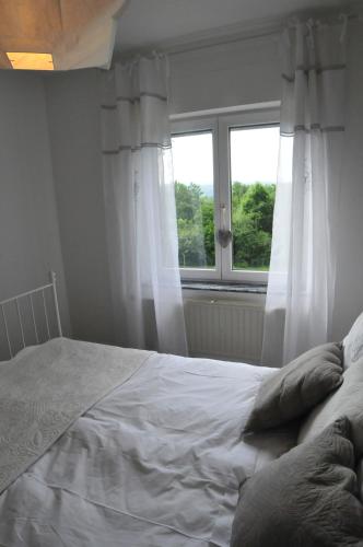 a white bed in a bedroom with a window at La Maison Des Artistes in Durbuy