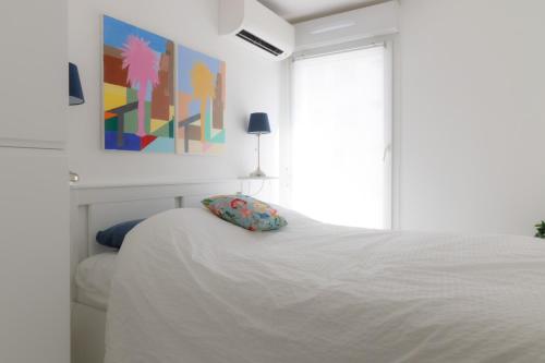 une chambre avec un lit blanc et un tableau au mur dans l'établissement appartement résidence riviera avec piscine, au Lavandou