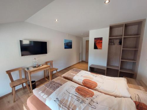 a bedroom with a bed and a table and a tv at B&B La Ferme De Pouillerel in La Chaux-de-Fonds