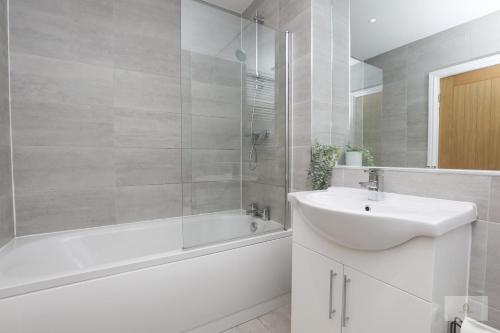 a white bathroom with a sink and a bath tub and a sink at Lovely 2-Bedroom Bungalow Sleeps 6 with Garden and Off Road Parking by Amazing Spaces Relocations Ltd in Crank