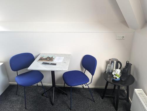 een tafel met drie blauwe stoelen in een kamer bij Hotel 1851 in Wijk bij Duurstede